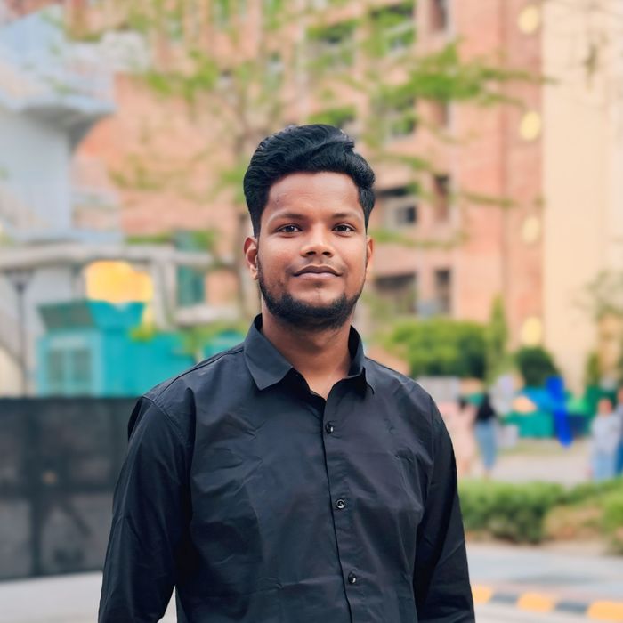 Casual portrait of a man in a black shirt, standing confidently outdoors.